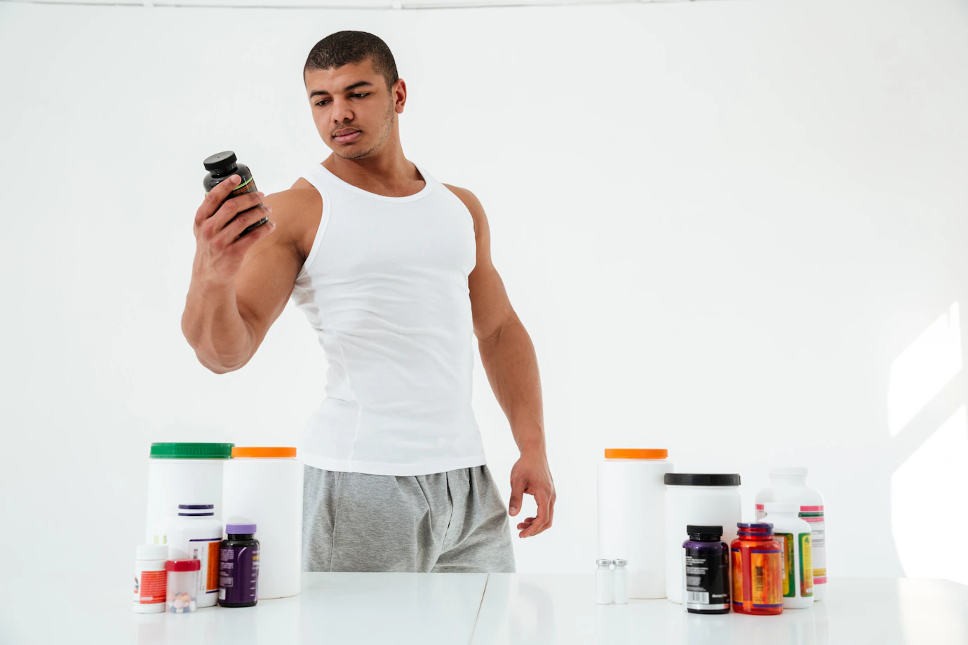 A strong young man holding a bottle of Fat Burn supplement.